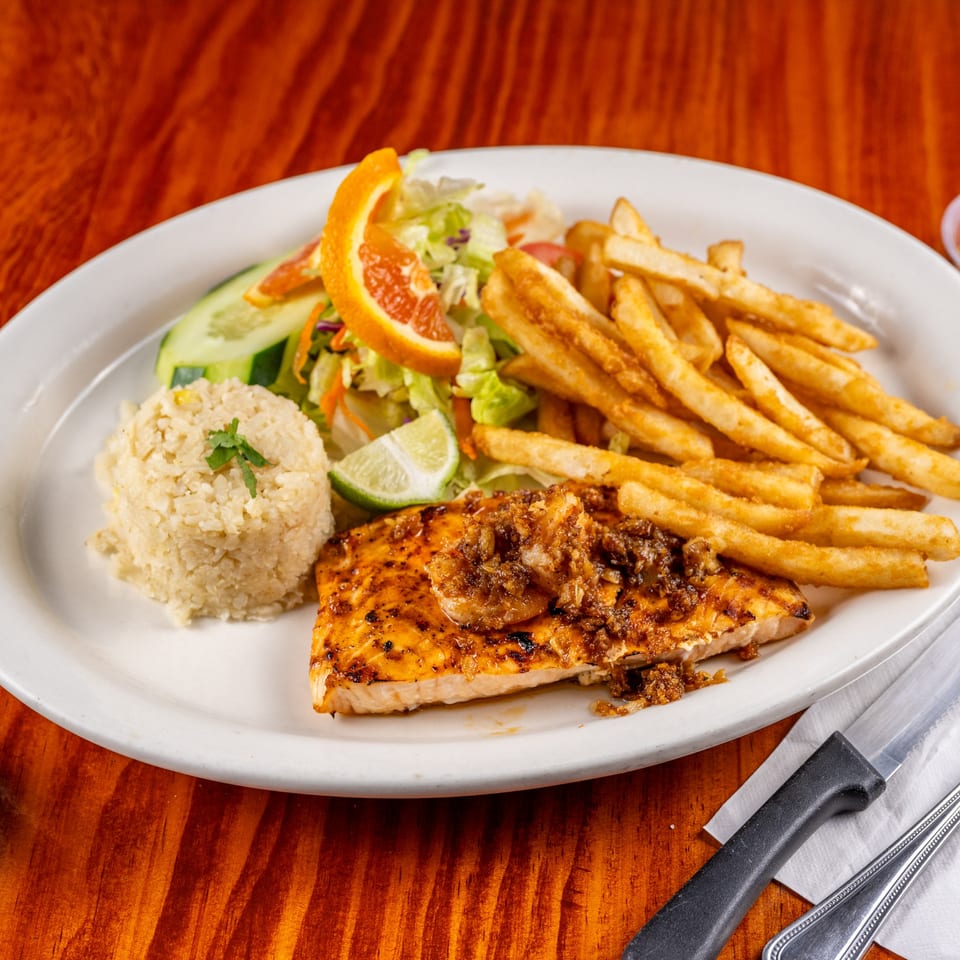 Grilled fish fillet topped with shrimp, served with rice, fries, and a fresh salad.