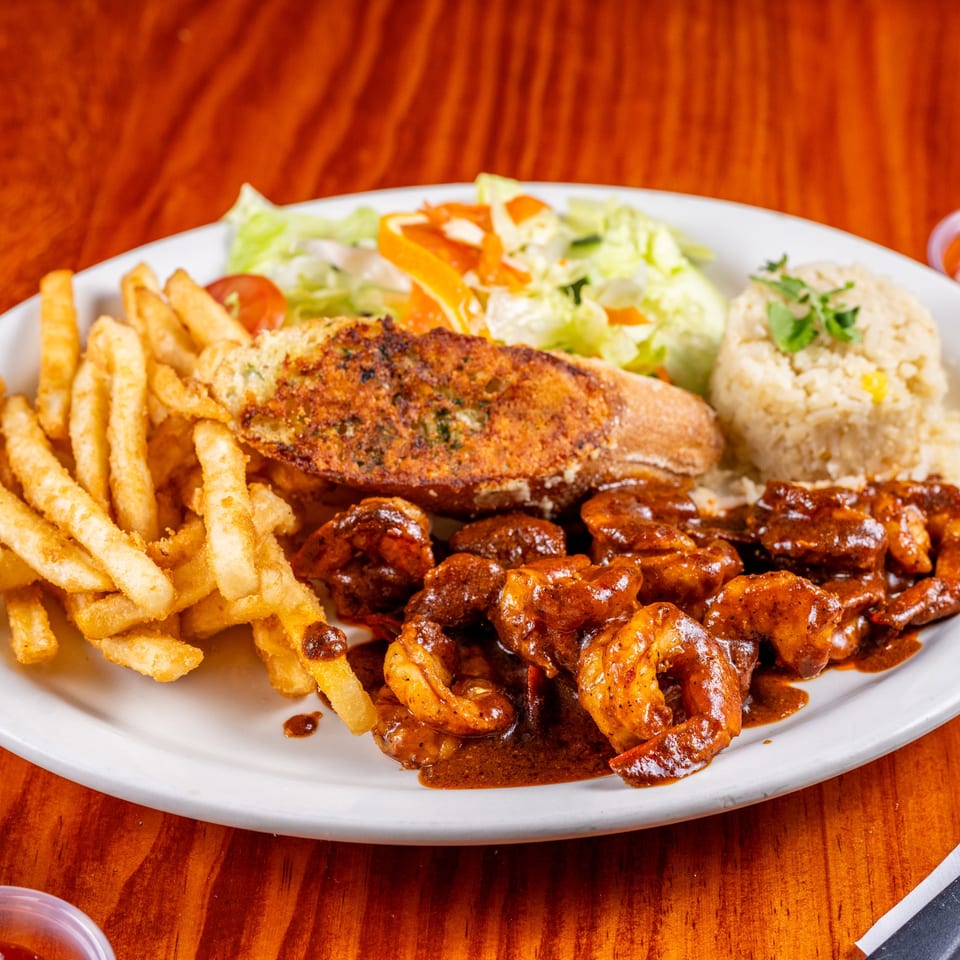 El Anzuelo's shrimp dish with fries, garlic bread, rice, and a side salad on a white plate.